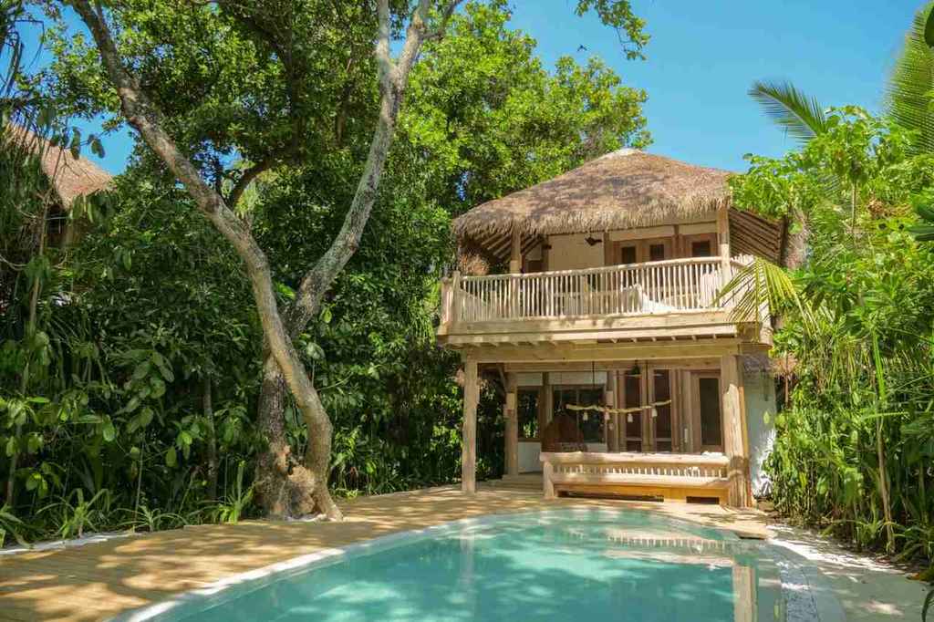 Imagem de piscina e chalé em estilo praiano indicando os melhores Resorts nas Maldivas